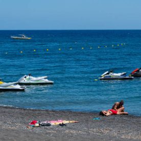 Perissa, Greece - July 18 2019:   Four jetskis awaiting tourists are anchored in the Aegean sea just off the Perissa Beach
