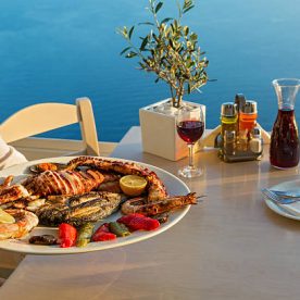 Dinner with seafood and red wine on the background of sea sunset