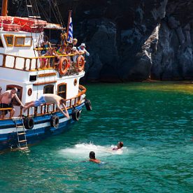 "Palea Kameni, Greece - September 8, 2011: Tourists jumping from a boat into the water to swim to the Palea Kameni hot springs in Santorini"