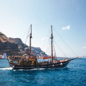 Santorini, Greece - June 10, 2019: Tourists ship full of tourists sailing out of the Old Port of Fira. Ship going towards Palea Kameni and Nea Kameni, small uninhabited volcanic islands at the center of the Santorini Caldera. It is a popular spot for waterside trips.