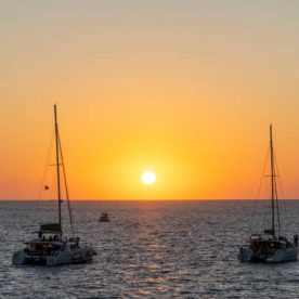 Sunset with a round and orange sun in Santorini, in the Greek islands during a summer clear day