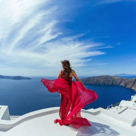 Woman in red dress aerial on the roof of island Santorini